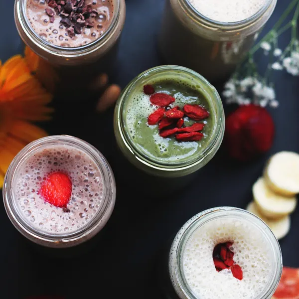 Smoothies in glass jars topped with berries, seen from above