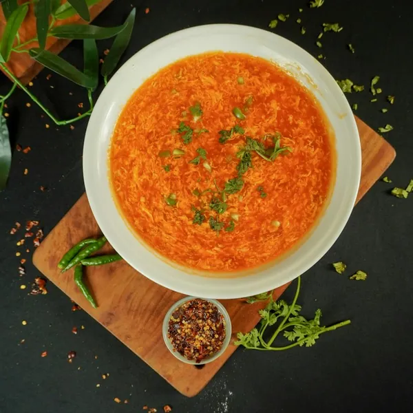A bowl of orange lentil soup topped with herbs