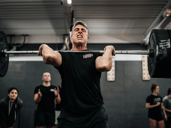 A man lifting a barbell in a gym