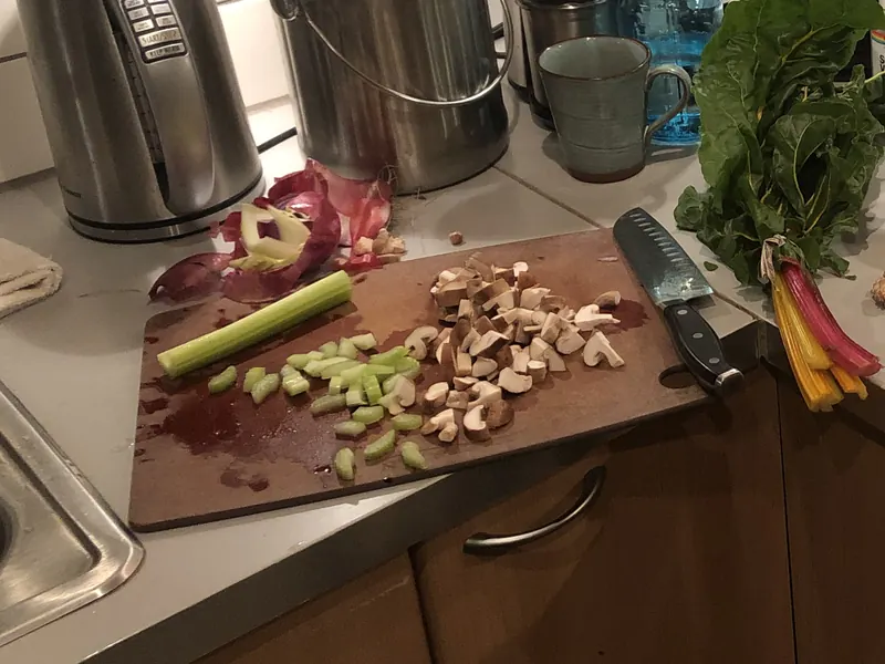 Chopped celery and mushrooms on a cutting board in a home kitchen