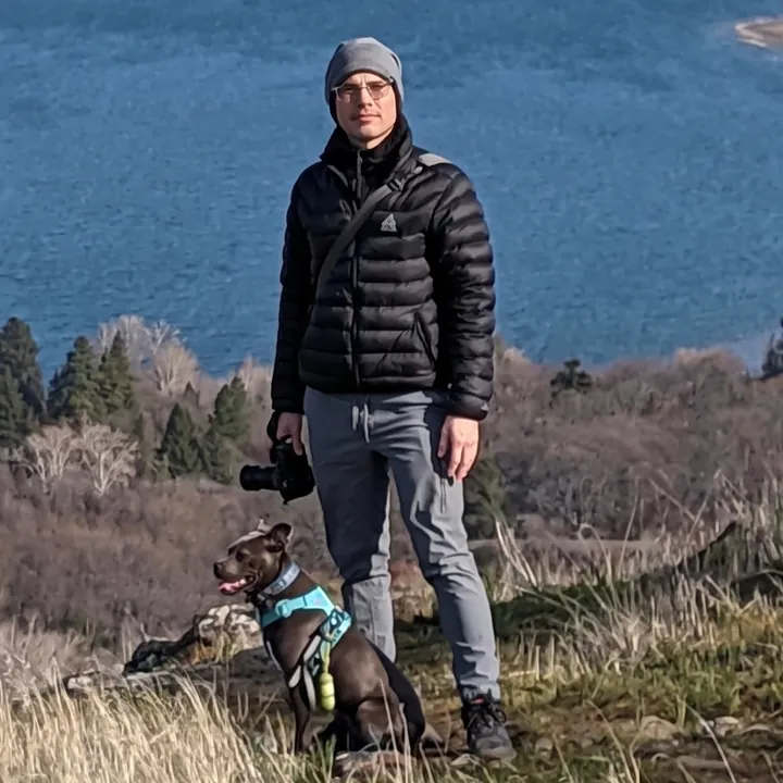 JT Root on a hike with a dog, a river valley behind him.